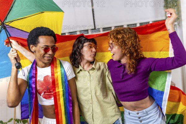 Non binary and transgender people dancing waving rainbow lgbt flag celebrating a party at home
