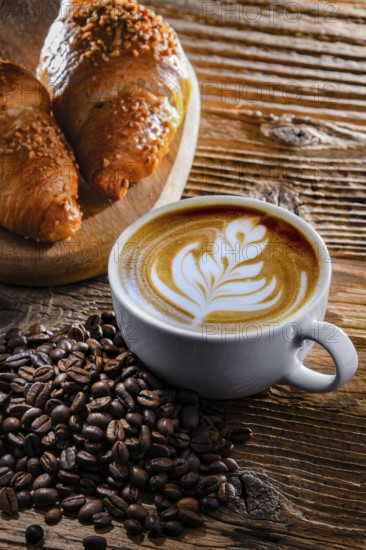 Composition with a cup of coffee and two croissants on an old wooden table