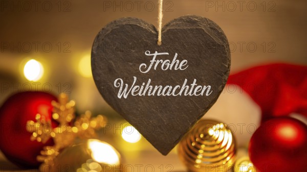 Christmas greetings: Heart with the inscription FROHE WEIHNAHCHTEN in front of Christmas