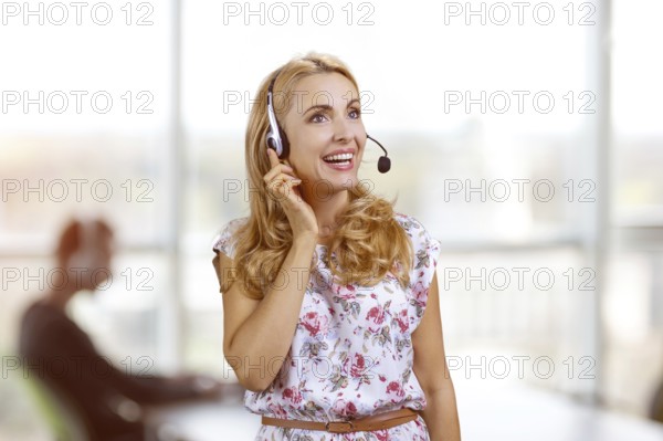 Portrait of smiling blondie wearing headset in office. Female customer support operator