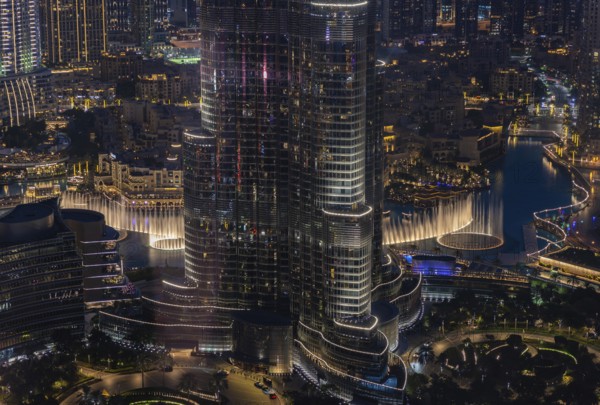 A picture of the Dubai Fountain Show, at night, and the bottom of the Burj Khalifa, next to other