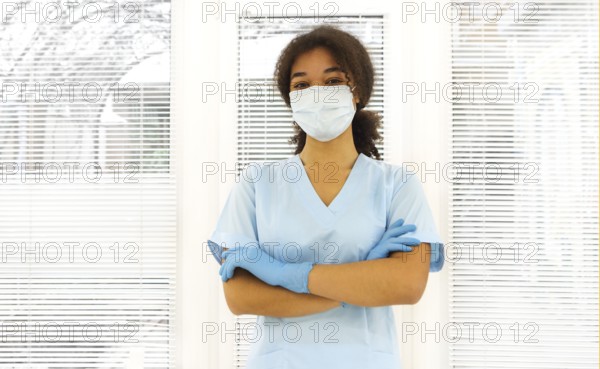 Young tired overworked african american medical worker wearing protective face mask looking to the