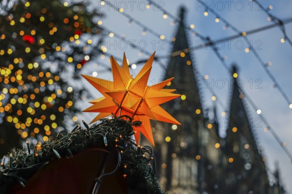 Christmas market at Cologne Cathedral, shining yellow star on a Christmas stall with fairy lights