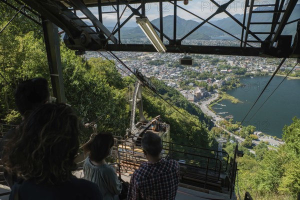 A group of tourists look down on the upcoming cable car from the Mt. Fuji Panoramic Ropeway to the