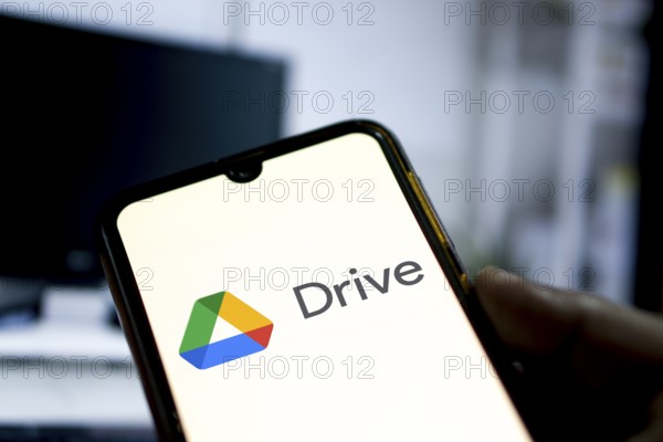 Man holding a smartphone with Google Drive cloud storage app on smartphone.