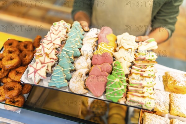 Close-up of a male baker offering a tray with Christmas cookies at shop