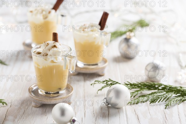 Eggnog with cinnamon and nutmeg for Christmas and winter holidays. With Xmas decorations on wooden