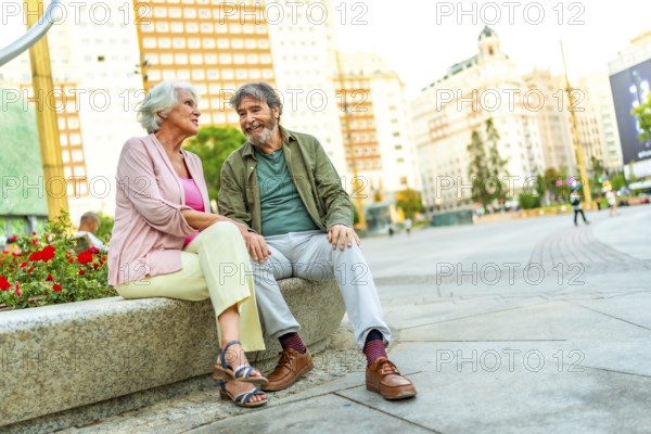 Happy senior couple enjoying a day in the city sitting on urban bench