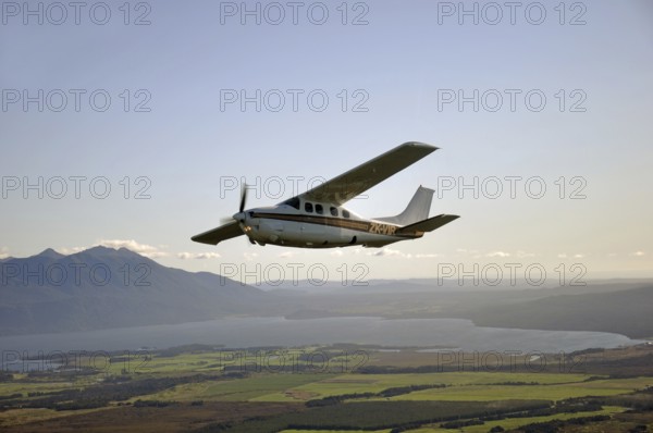 Cessna 210 light aircraft flying over Lake Brunner, Westland, New Zealand, Oceania