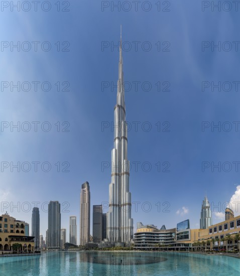 A picture of the Burj Khalifa towering the nearby Downtown Dubai buildings and the blue waters of