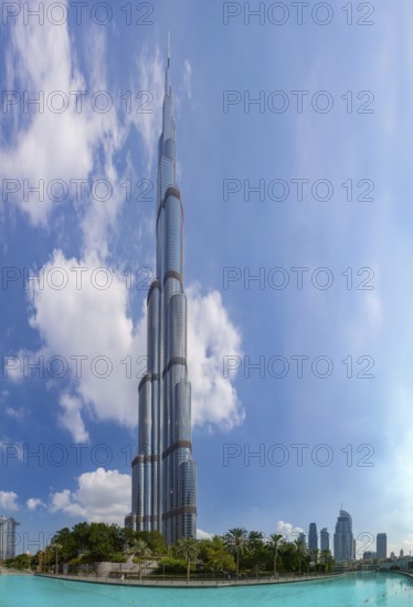 A picture of the Burj Khalifa towering the nearby Downtown Dubai buildings and the blue waters of