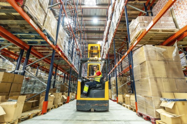 Full length wide photo of a worker using forklift in a storage warehouse