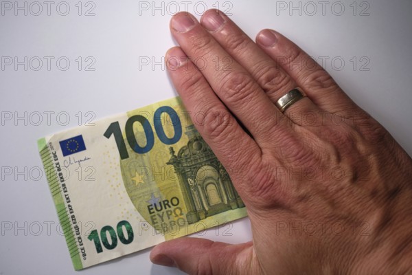 Symbol photo for cash, 100 euro note half covered by a hand, North Rhine-Westphalia, Germany,