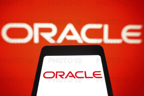 In this photo illustration, the Oracle Corporation logo is displayed on a smartphone screen and in