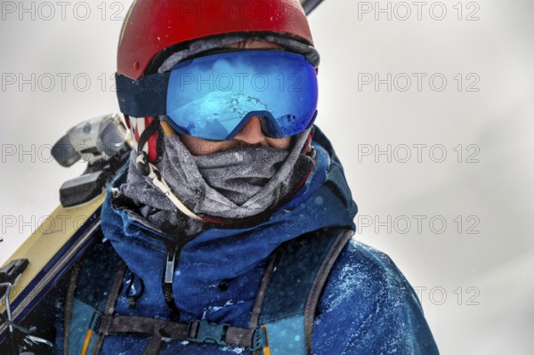 Closeup portrait of ski goggles of a man with reflection of snowy mountains. The mountain range is