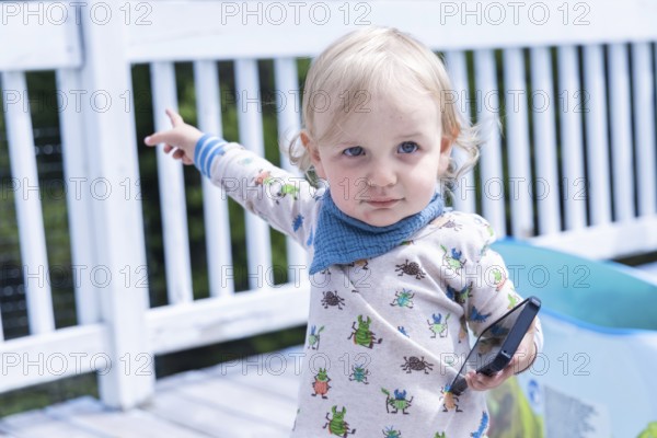 Closeup portrait of a 3 year old boy, with pale white complexion and cute baby grower holding a