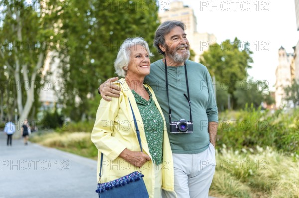 Mature caucasian man with a camera and wife visiting an urban park walking together