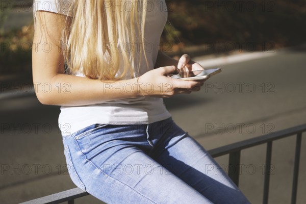 midsection of unrecognizable young woman using her smartphone or mobile phone outside on city