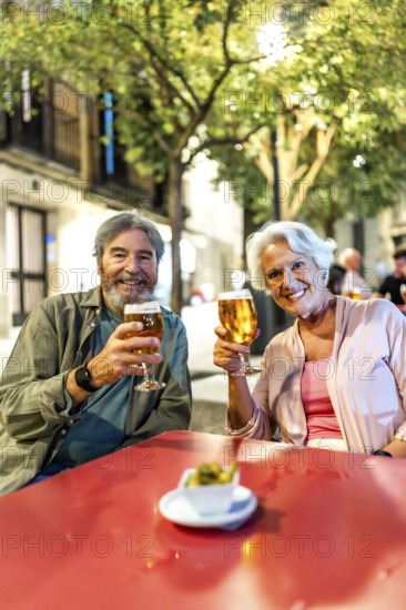 Vertical photo of a senior couple enjoying tapas and beer in the city of Madrid, Spain, Europe