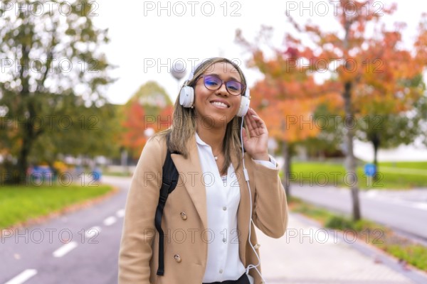 Latin blonde confident businesswoman listening to music walking along the city