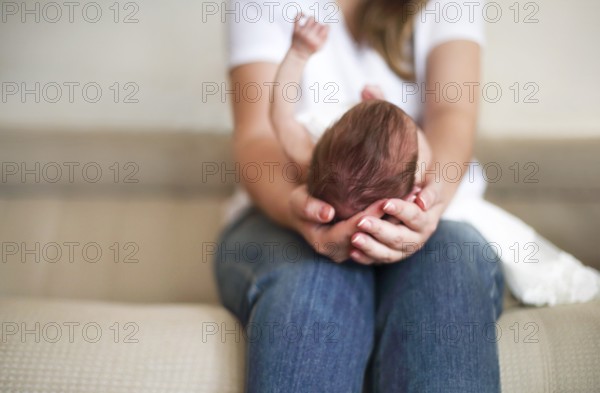 Young mother holding her newborn child. Mom nursing baby. Family at home Close up