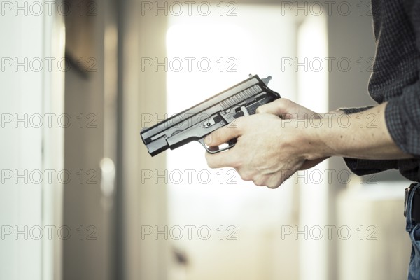 Undercover police agent is holding a black weapon in his hand, ready for shoot