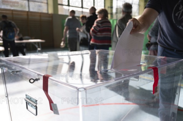 Voter's hand putting the vote into the ballot box. The inscription on the seal in Polish Electoral