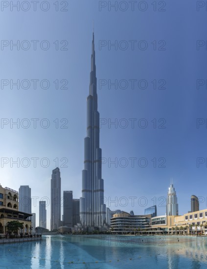 A picture of the Burj Khalifa towering the nearby Downtown Dubai buildings and the blue waters of