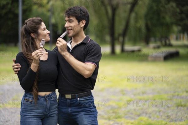 Young couple in love eating a popsicle in the park