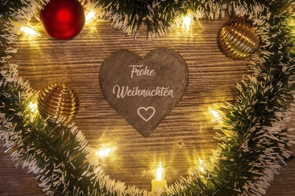 Christmas greetings: Heart with the inscription FROHE WEIHNACHTEN with Christmas decorations