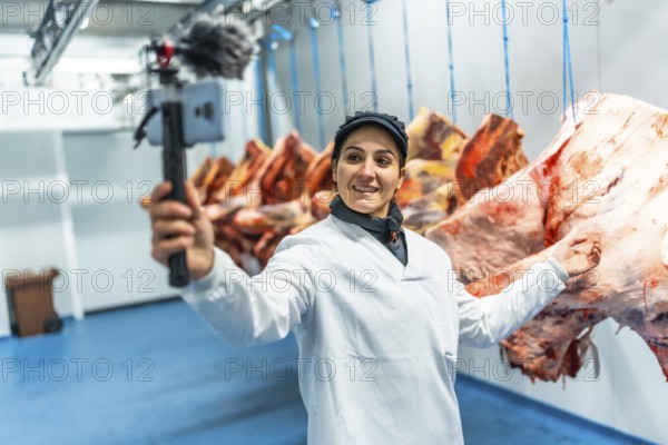 Caucasian adult female vlogger talking to audience recording inside the cold storage room in a meat