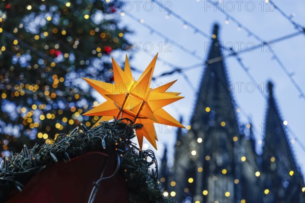 Christmas market at Cologne Cathedral, shining yellow star on a Christmas stall with fairy lights