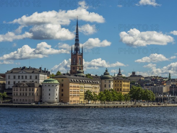 Church tower and historic buildings on the waterfront under a blue sky with clouds, archipelago,