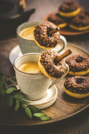 Two cups of Caffe Americano with small chocolate donuts