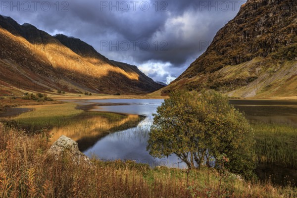 Mountains reflected in lake, evening light, cloudy mood, autumn, Loch Achtriochtan, Glencoe,