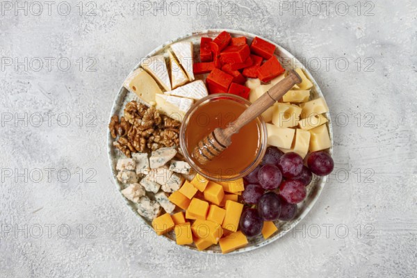 Appetizer, assorted cheese, with nuts and honey, on a round plate, top view, no people