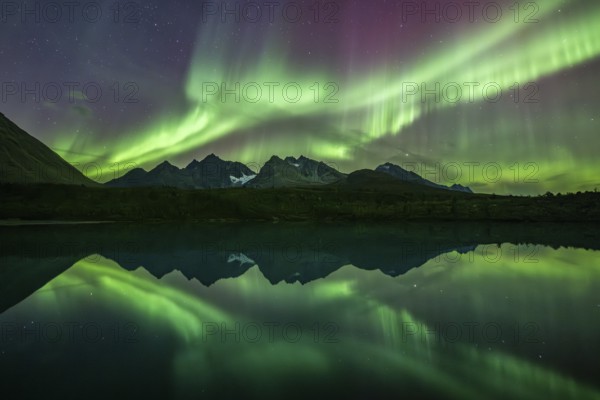 Northern lights over the mountains of the Lyngen Alps, reflection in lake, Lyngen, Norway, Europe