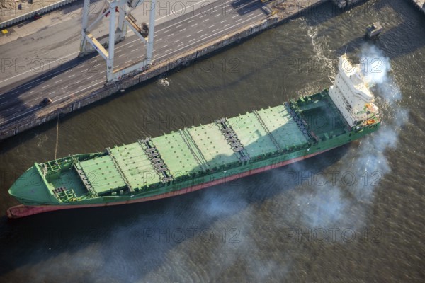 Aerial view of a cargo ship in the port of Hamburg with a lot of exhaust gas, emissions, smoke,