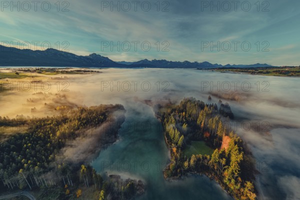 Autumn sunrise in the foothills of the Alps with fog at Illasbergsee and Forggensee near Halblech