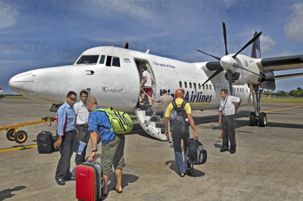 Propeller aircraft, prop jet Fokker 50, former Riau Airlines, passengers and staff at the airport