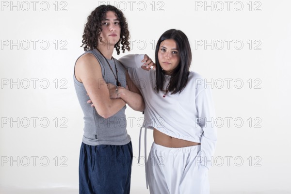 Portrait of a young couple dressed in yoga clothes looking ti the camera white background. Studio