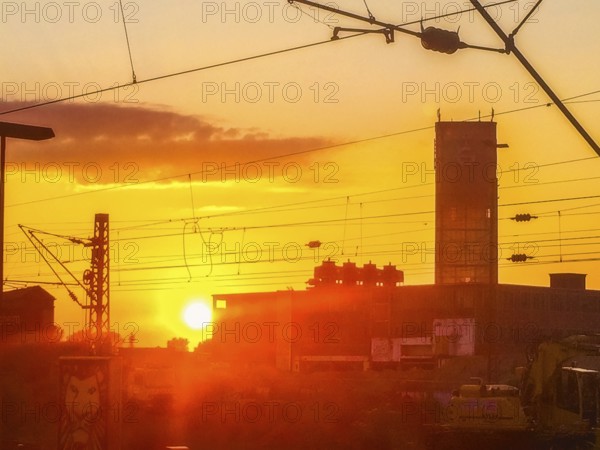 Sunset behind buildings with power lines and orange-coloured sky, Gerresheimer Germany, Lost Place,