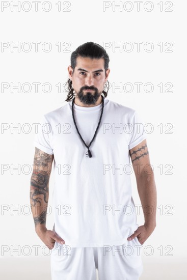 Portrait of a man dressed in white yoga clothes over white background while looking at camera.