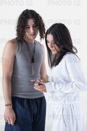Portrait of a young couple dressed in yoga clothes looking a smartphone over white background.