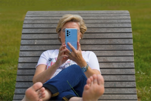 Woman on a wooden couch holding her mobile phone