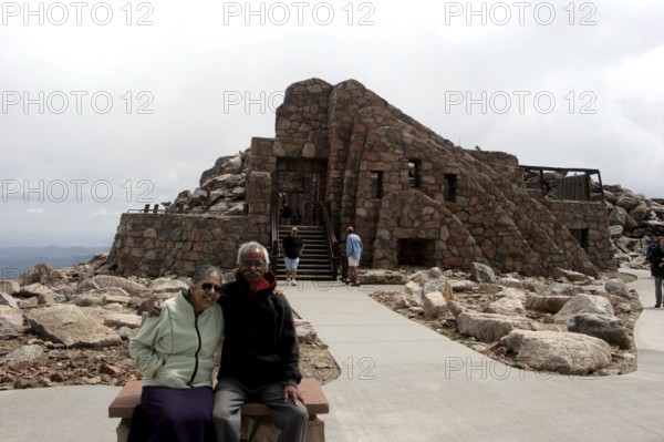 Old man and woman sitting in front of Crest House built in 1939