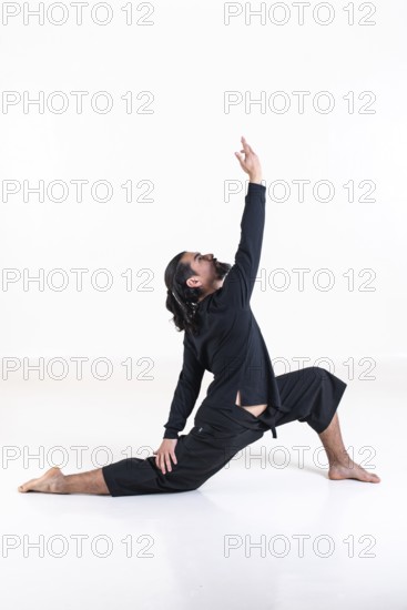 A man dressed in black doing yoga over white background. anjaneyasana yoga pose. Studio shot