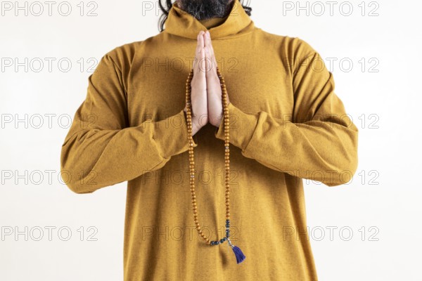 Close up of a man clasping hands while holding a japa mala over white background