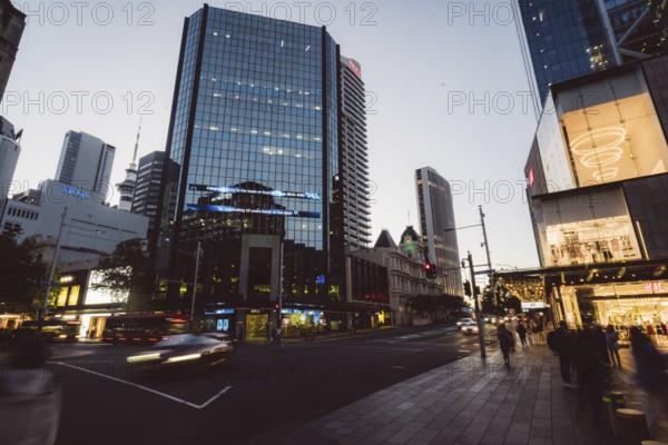 View of a busy street scene with modern skyscrapers and passers-by at dusk, new Zealand stock
