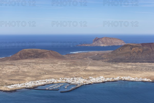 Aerial view of the island of La Graciosa with harbour, surrounded by desert and blue sea, Canary